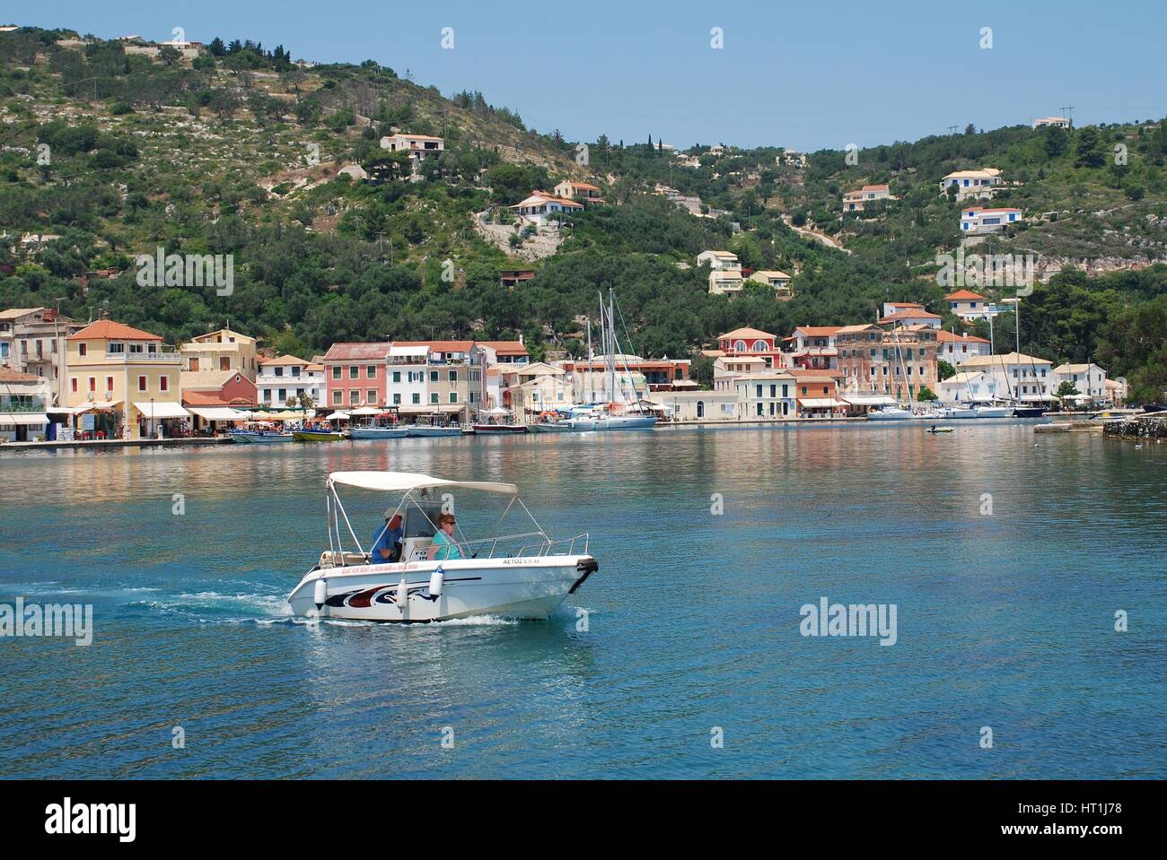 A small boat head out of Gaios harbour on the Greek island of Paxos. Stock Photo
