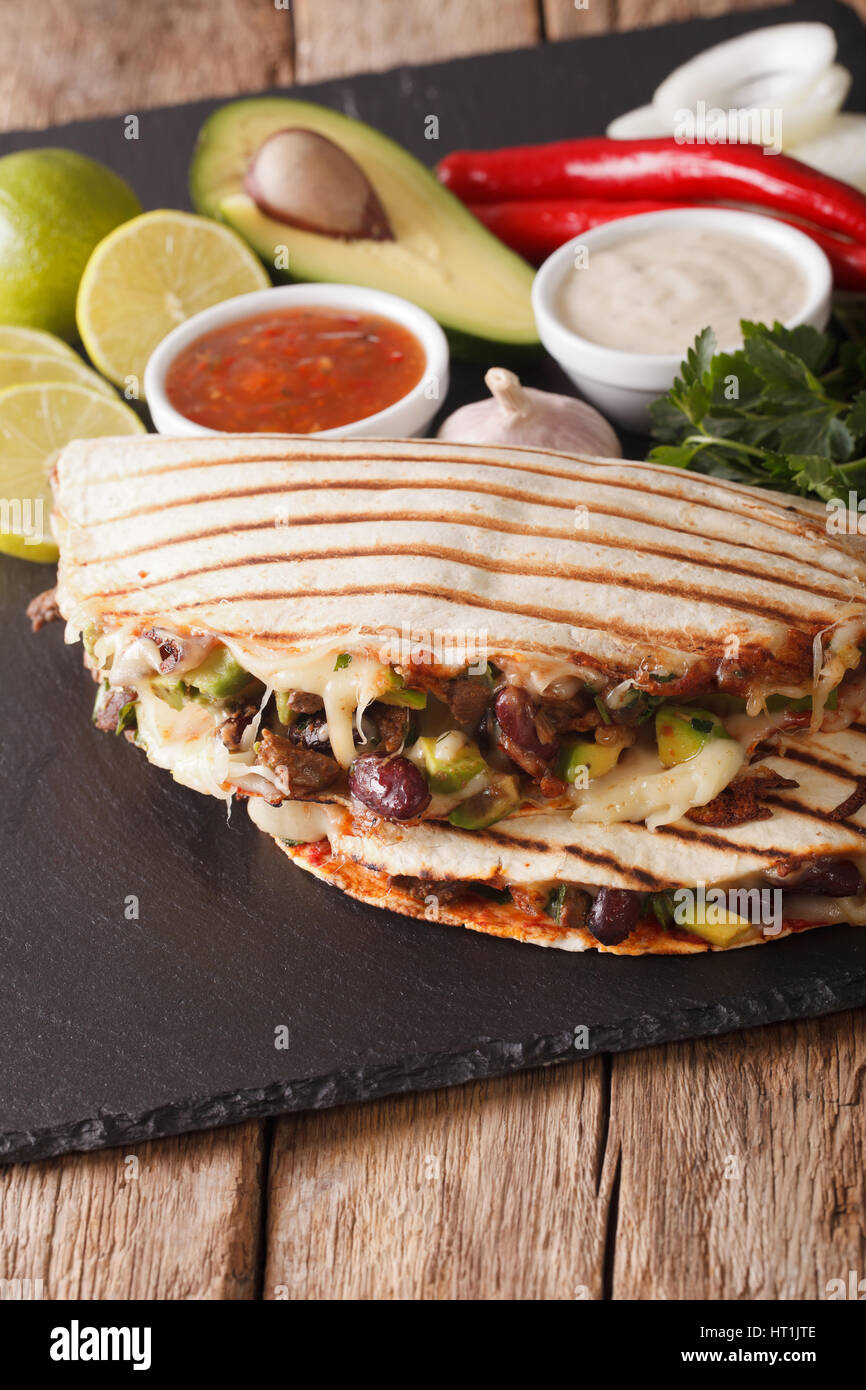 quesadilla with beef, beans, avocado and cheese close-up on the table. vertical Stock Photo