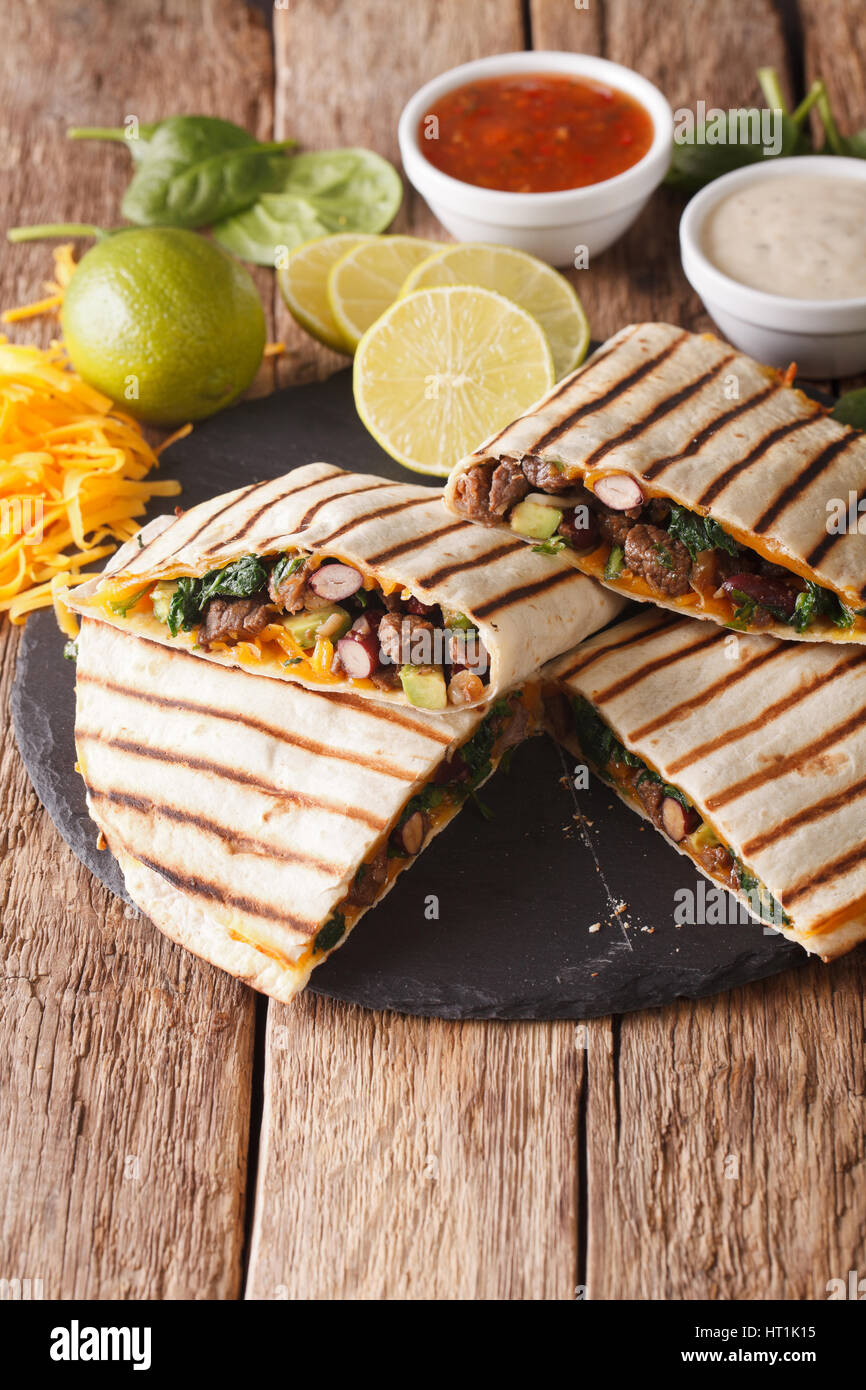 quesadilla with meat, spinach and cheddar cheese close-up on the table. vertical Stock Photo