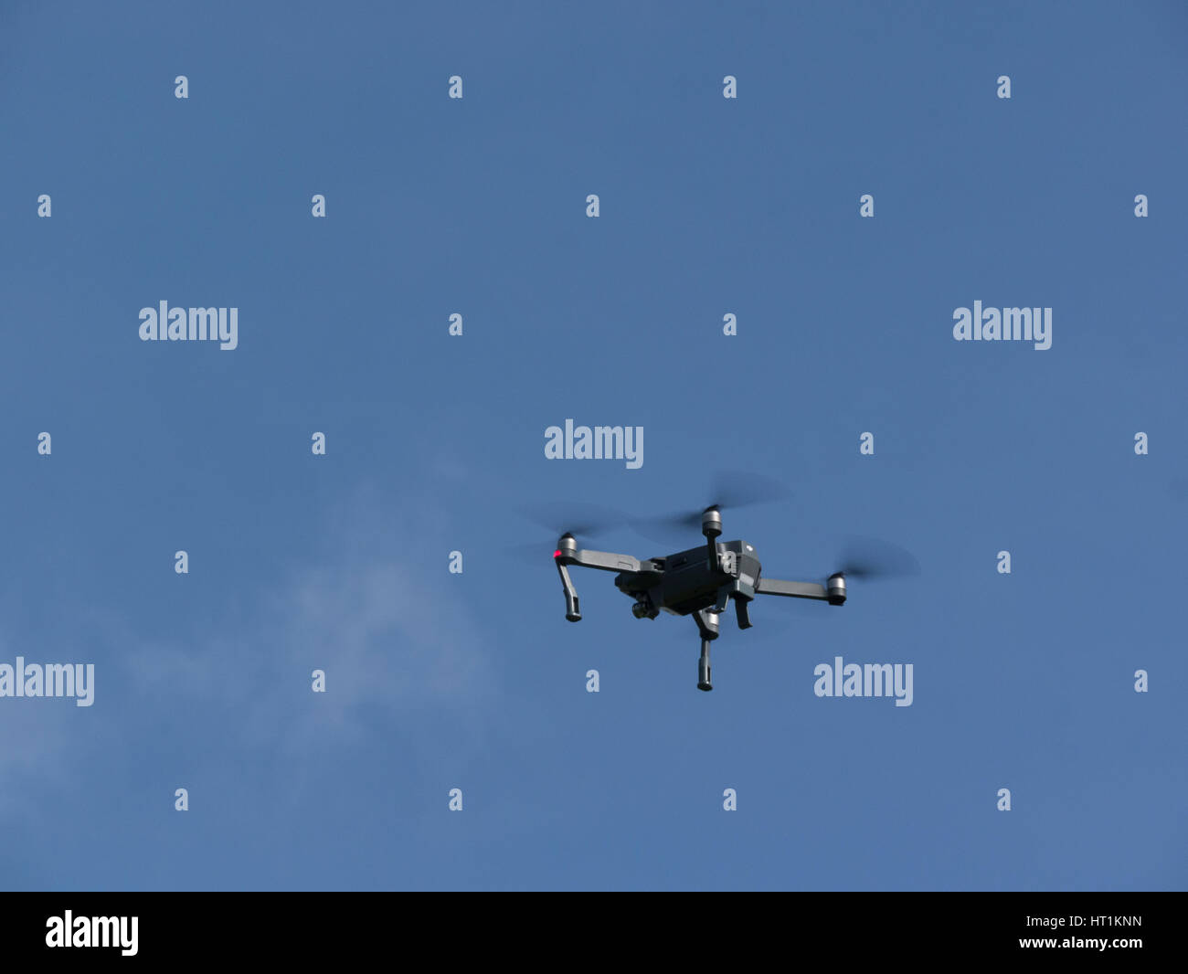 Drone flying in clear blue sky taking photographs Unmanned aerial vehicle intelligent flight system motion-sensitive auto stabilizers ultra portable Stock Photo