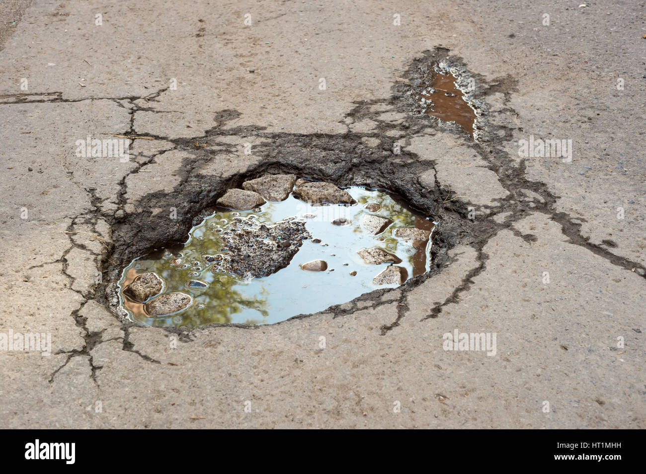 Large deep pothole with blue sky reflection in Montreal street, Canada. Stock Photo