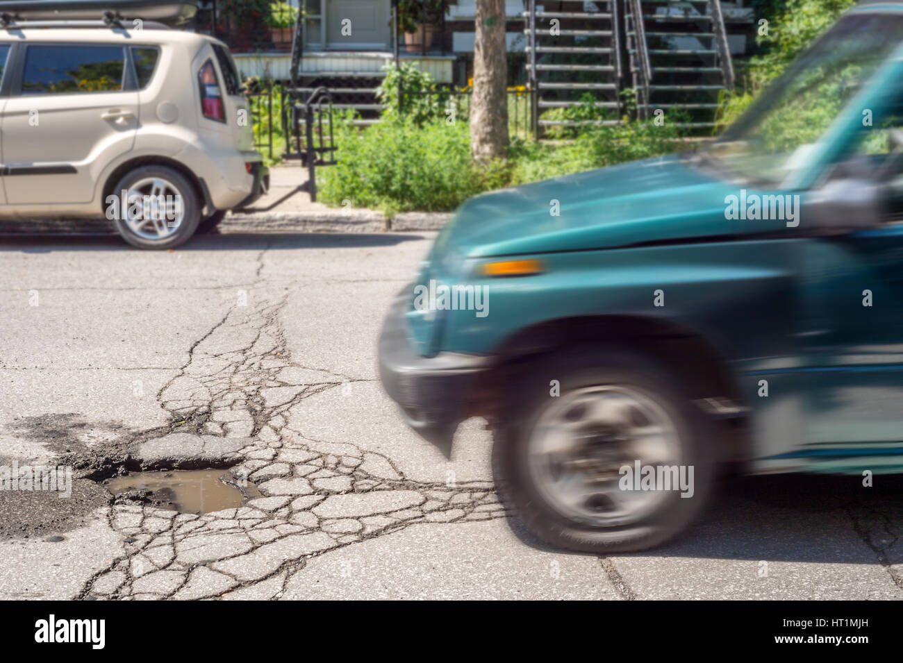 Large deep pothole with car approaching in Montreal street, Canada. Stock Photo
