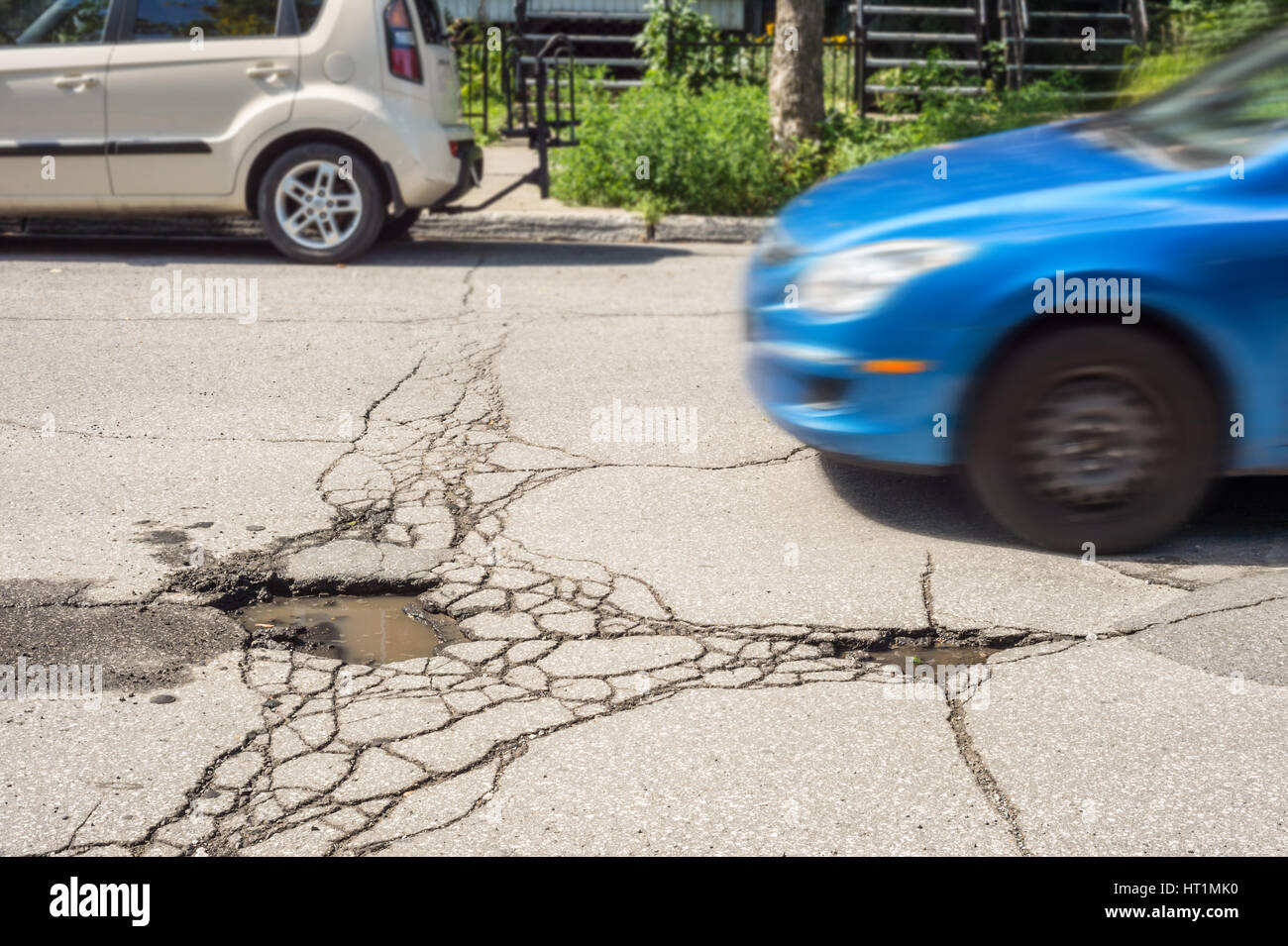 Large deep pothole with car approaching in Montreal street, Canada. Stock Photo
