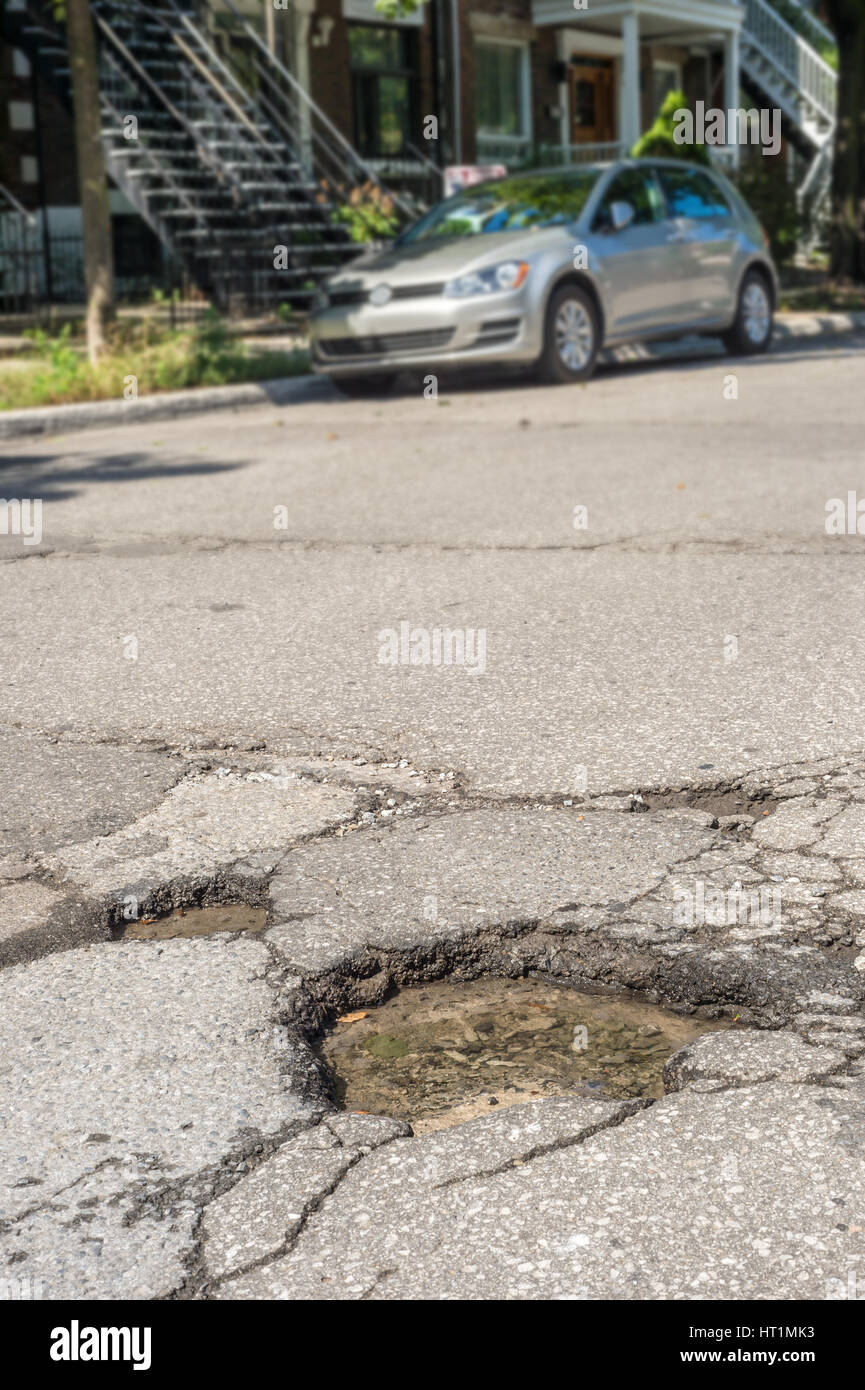 Large deep pothole with car in the background in Montreal street, Canada. Stock Photo