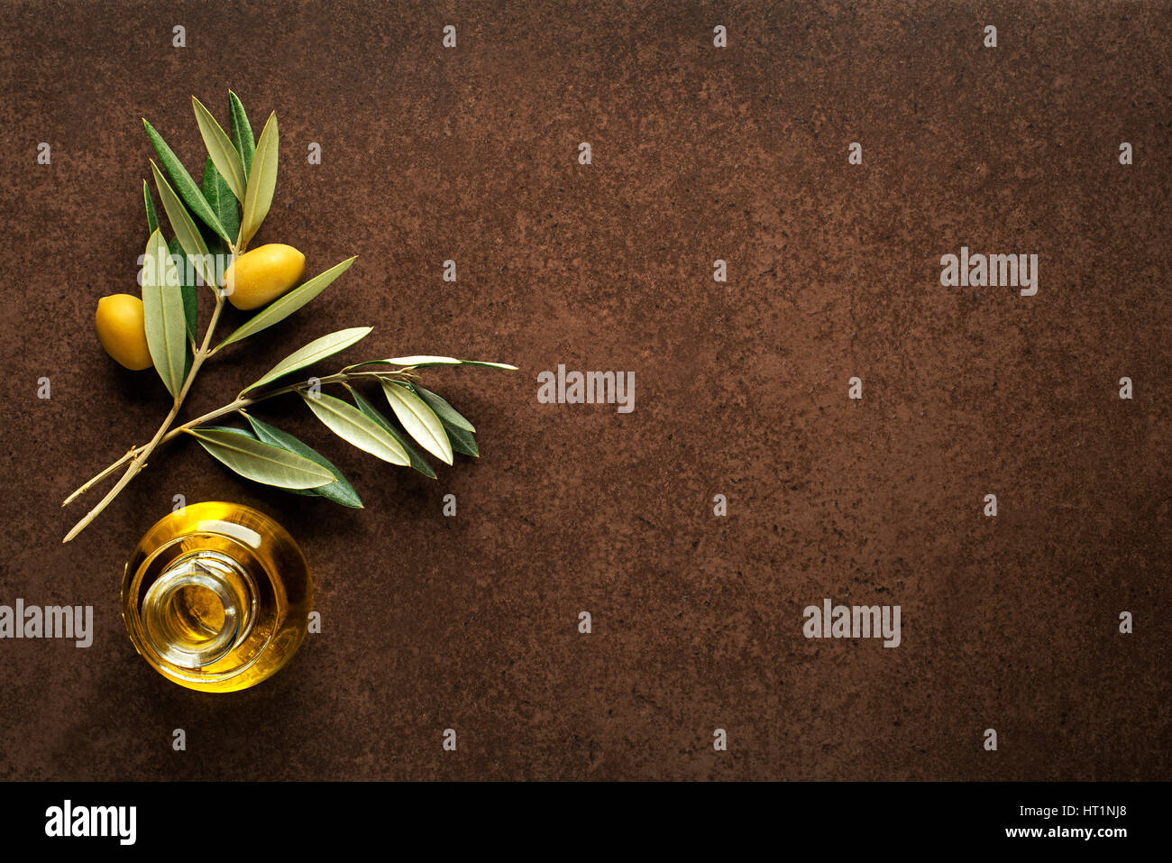 Olive oil and olive branch on brown table Stock Photo - Alamy