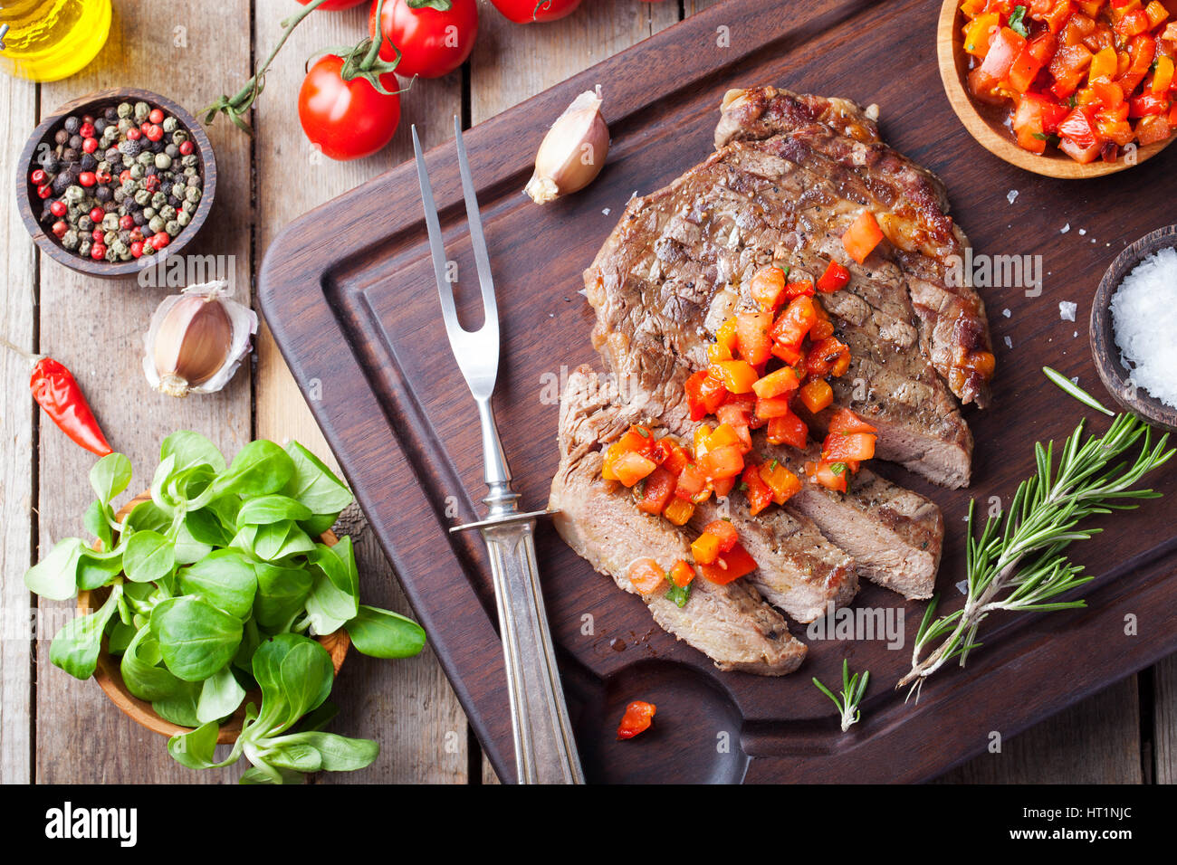 Beef steak well done with tomato and pepper salsa on a wooden