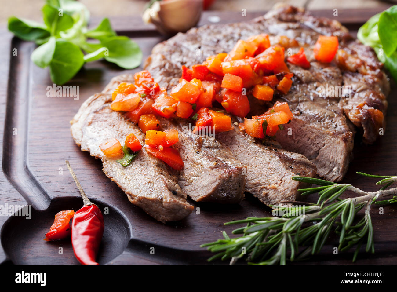 Beef steak well done with tomato and pepper salsa on a wooden