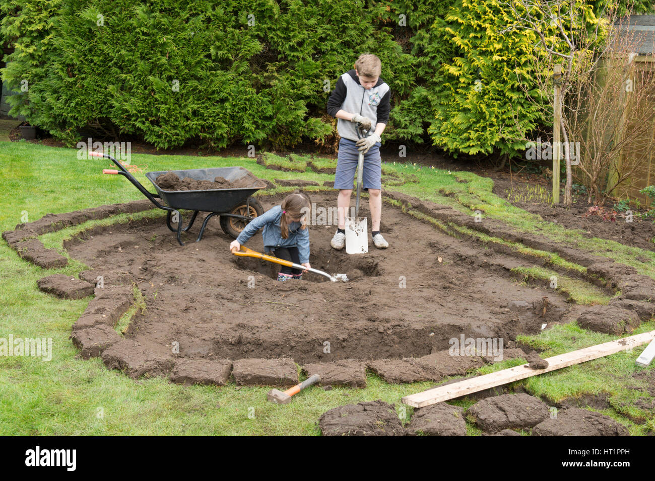 young girl and boy digging wildlife pond in garden Stock Photo