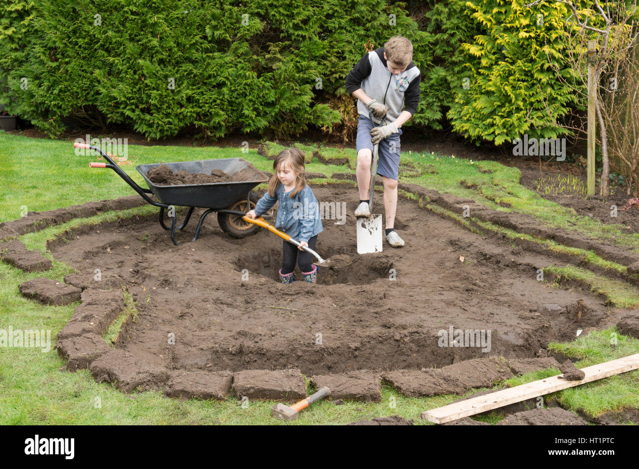 young girl and boy digging wildlife pond in garden Stock Photo - Alamy