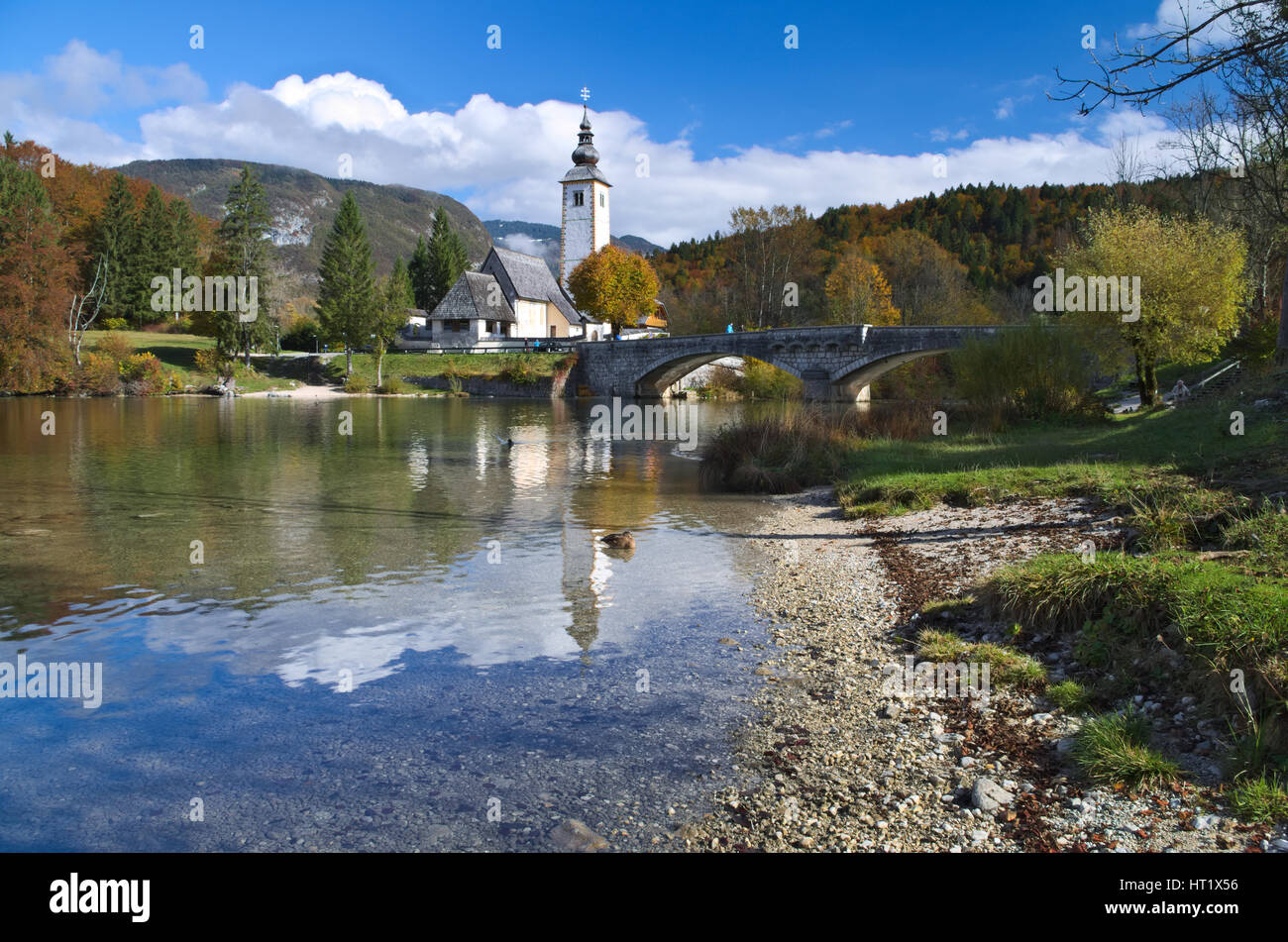 Autumn view of the stone bridge and the Church of St. John the Baptist at Lake Bohinj (Bohinjsko jezero), Slovenia Stock Photo
