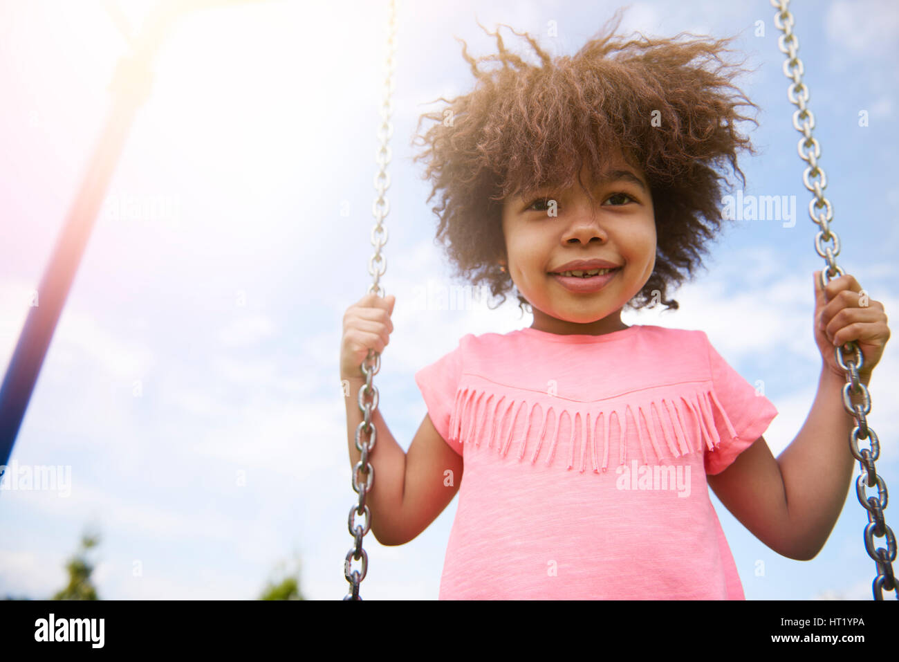 Cute little girl swinging in sunny day Stock Photo