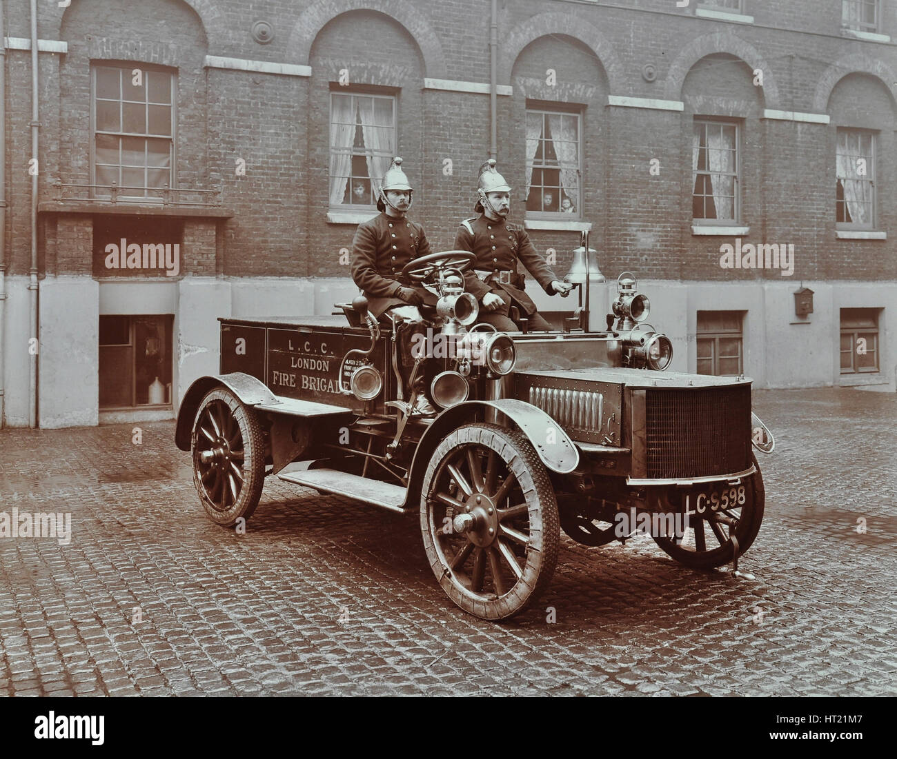 Firemen in brass helmets aboard a motor hose tender, London Fire Brigade Headquarters, London, 1909. Artist: Unknown. Stock Photo
