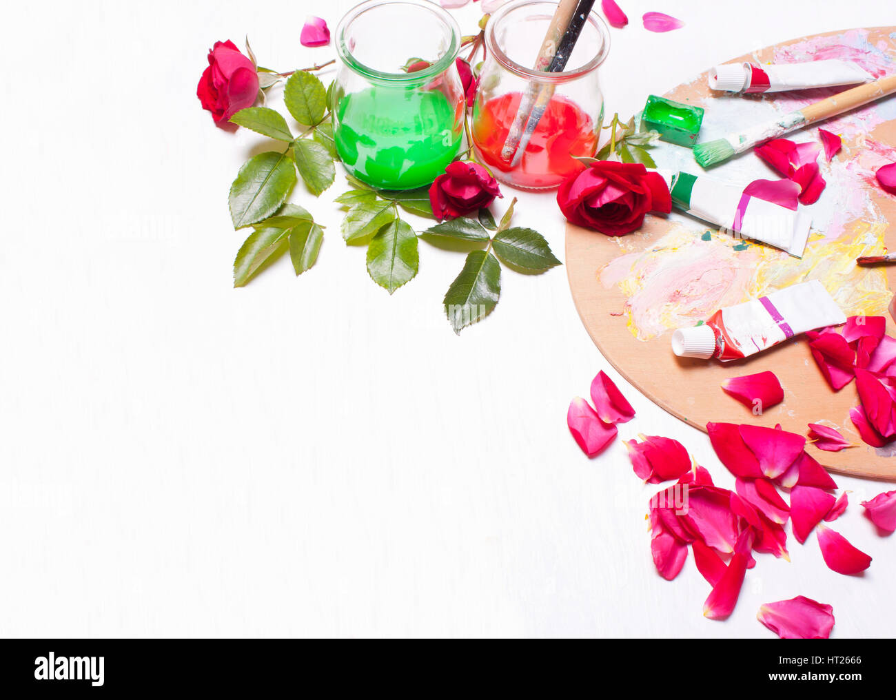 Paints and brushes with rose petals.Workplace of artist,designer.Concept art, creative.Top view background. Stock Photo