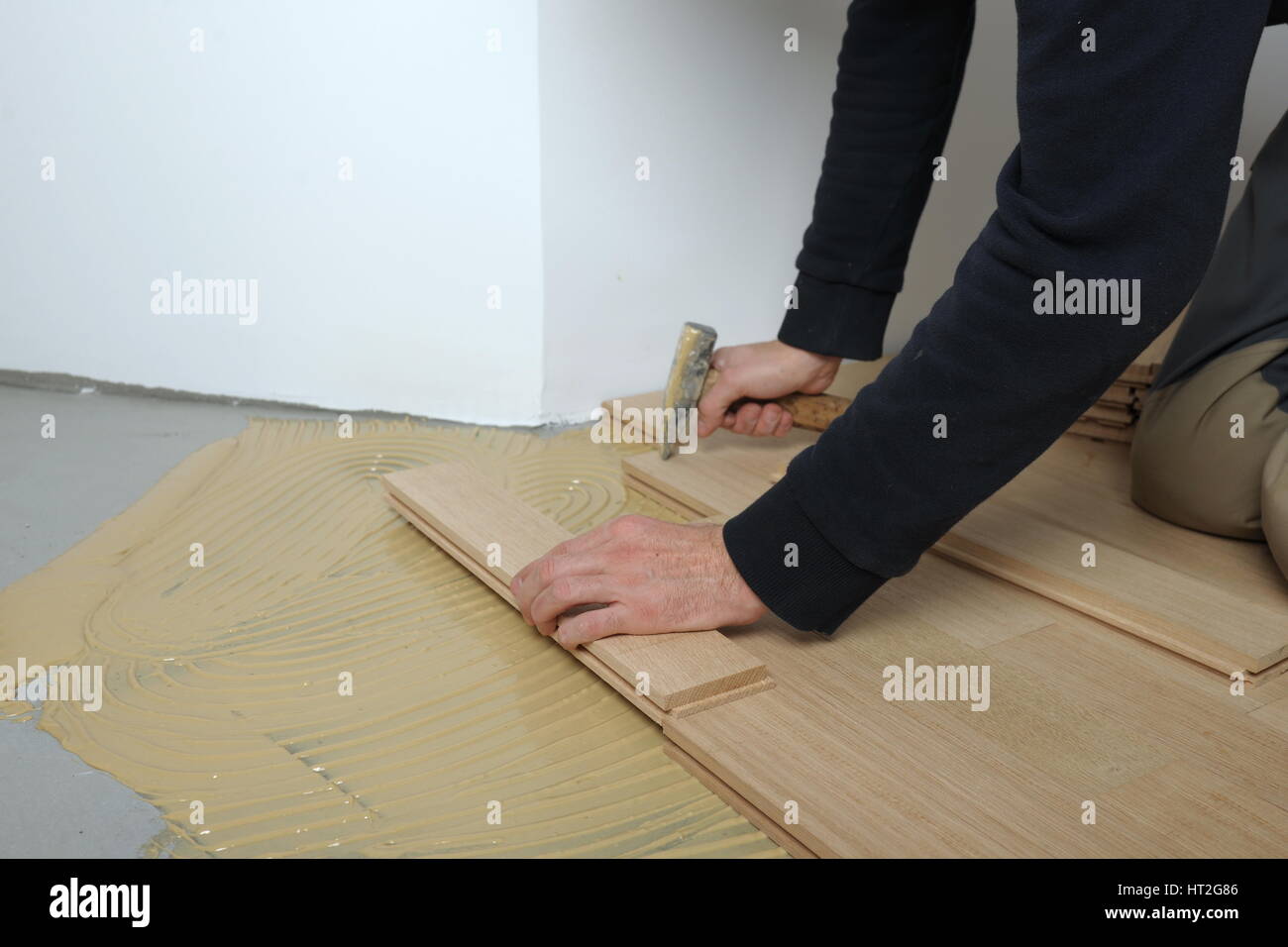 Worker Installing Wood Parquet Construction In A Renovated Room