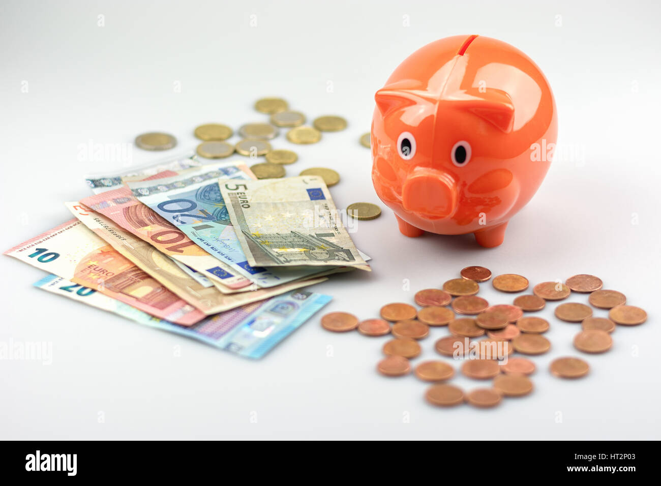 Piggy bank watching a stack of Euro banknotes and coins Stock Photo - Alamy