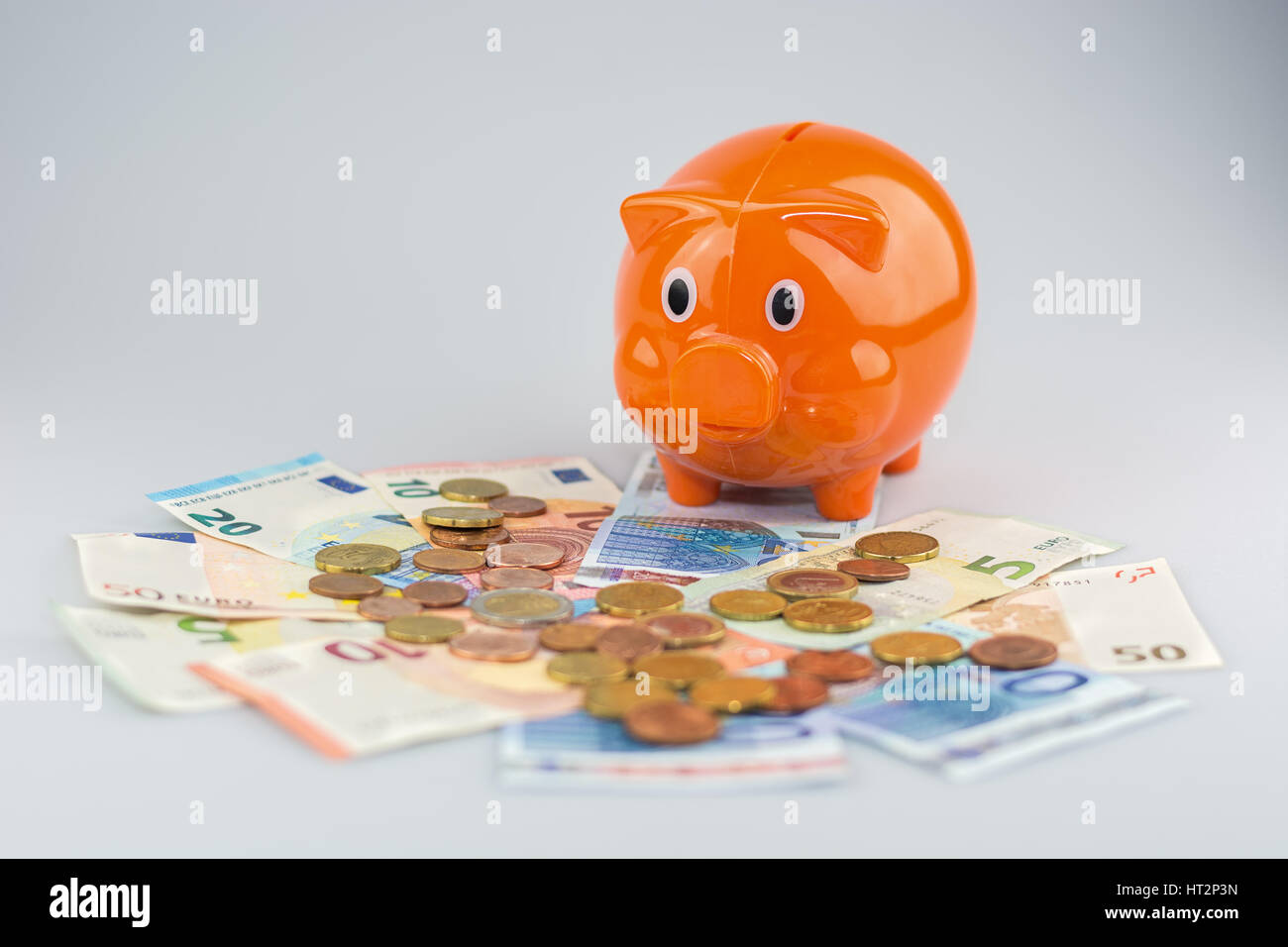 Piggy bank watching a stack of Euro banknotes and coins Stock Photo - Alamy