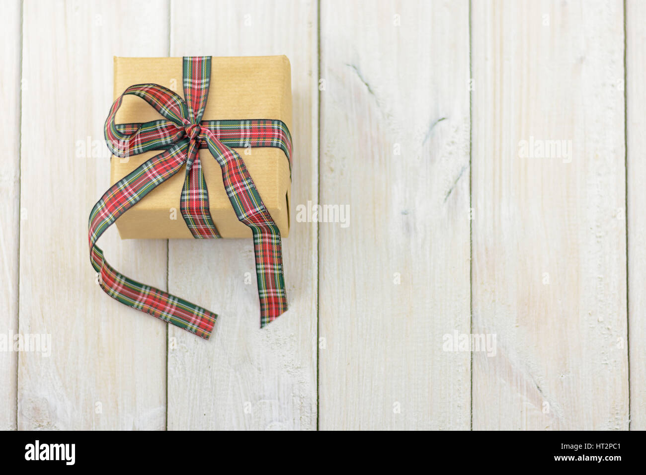 Box with a gift on a wooden table tied with colored ribbon. Stock Photo