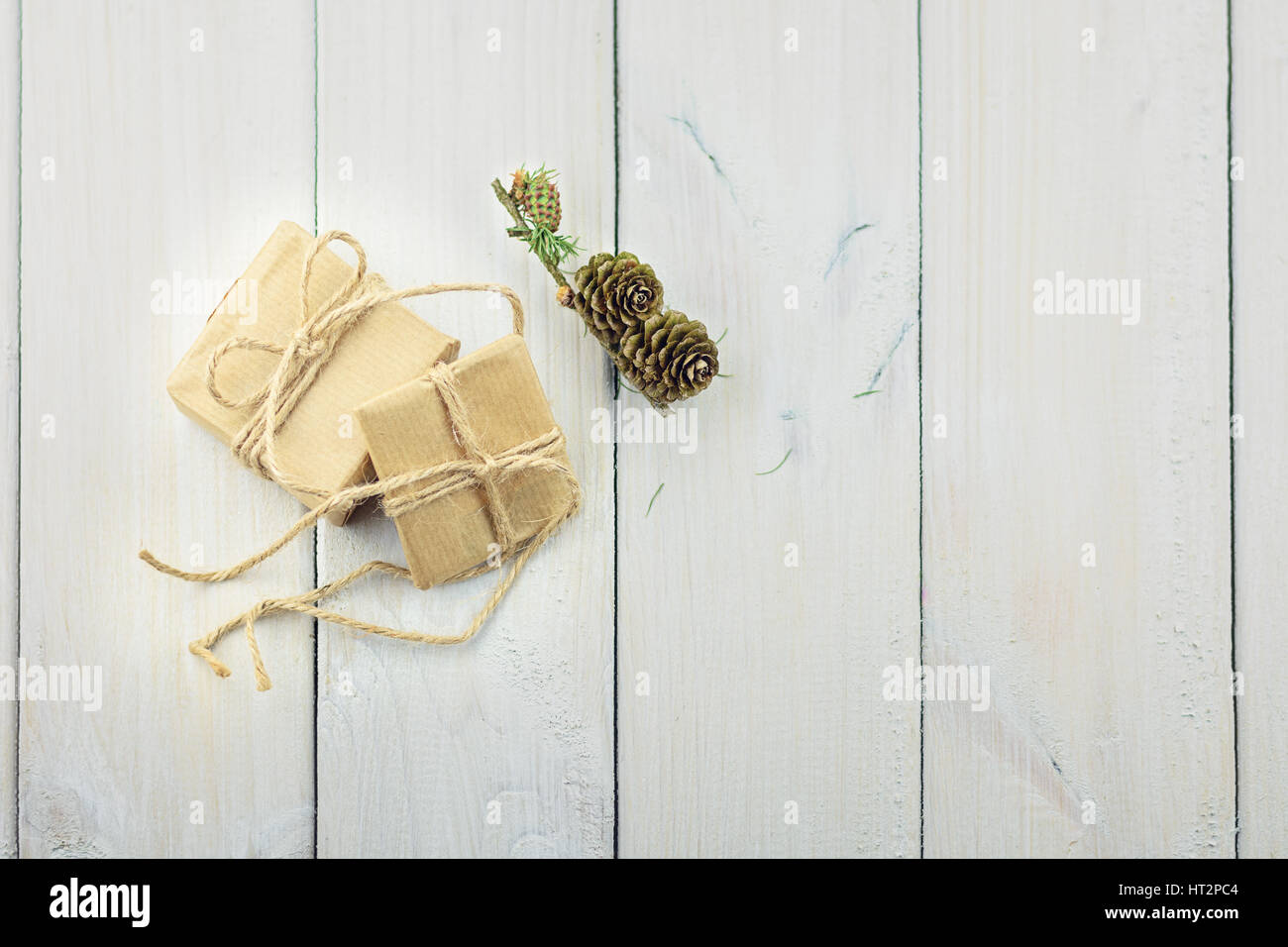 Two boxes with a gift on a wooden table tied with a rope decorated with a sprig of Christmas trees. Stock Photo