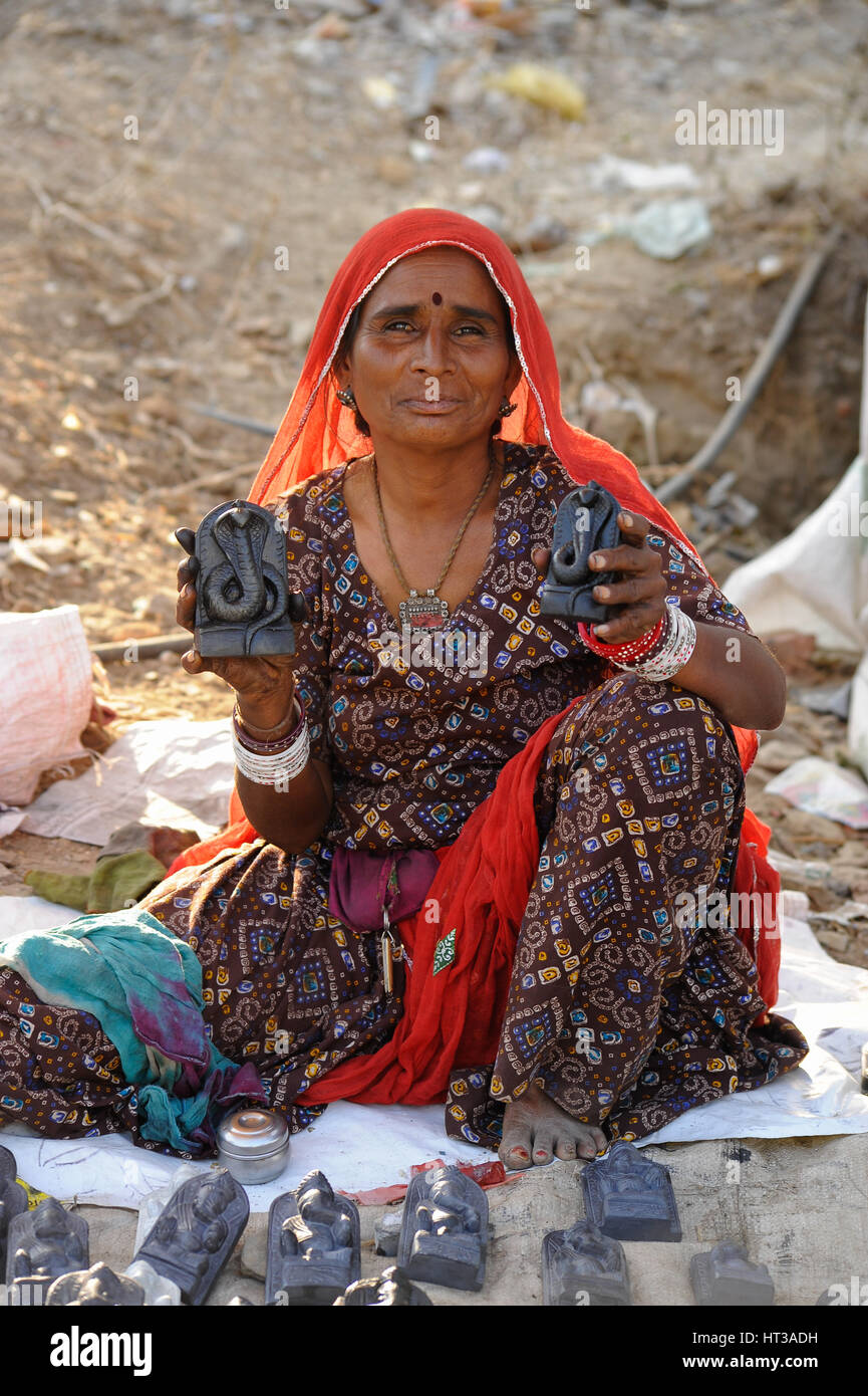A hawker holds up her wares: Stone statues depicting the Hindu cobra god Vasuki Stock Photo