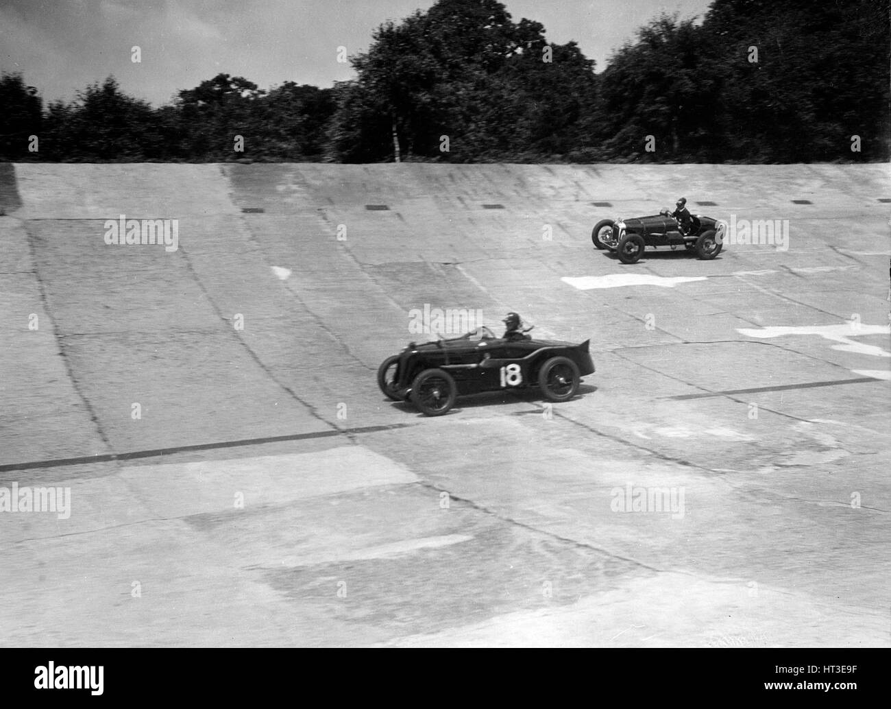 MG C type and Amilcar C6 racing on the banking at Brooklands. Artist: Bill Brunell. Stock Photo
