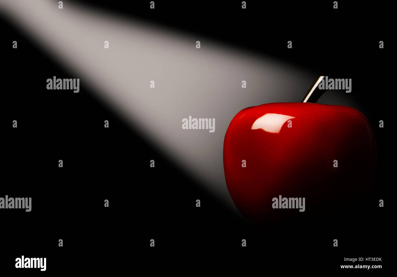 Red apple in a light beam on a black background. Stock Photo