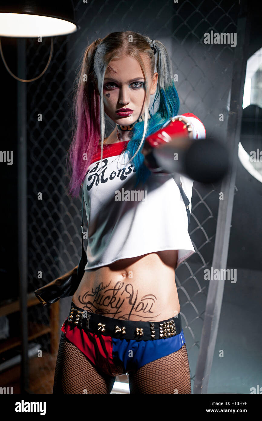 Girl in costume Harley Quinn. She stands with a bat. Cosplay Stock Photo