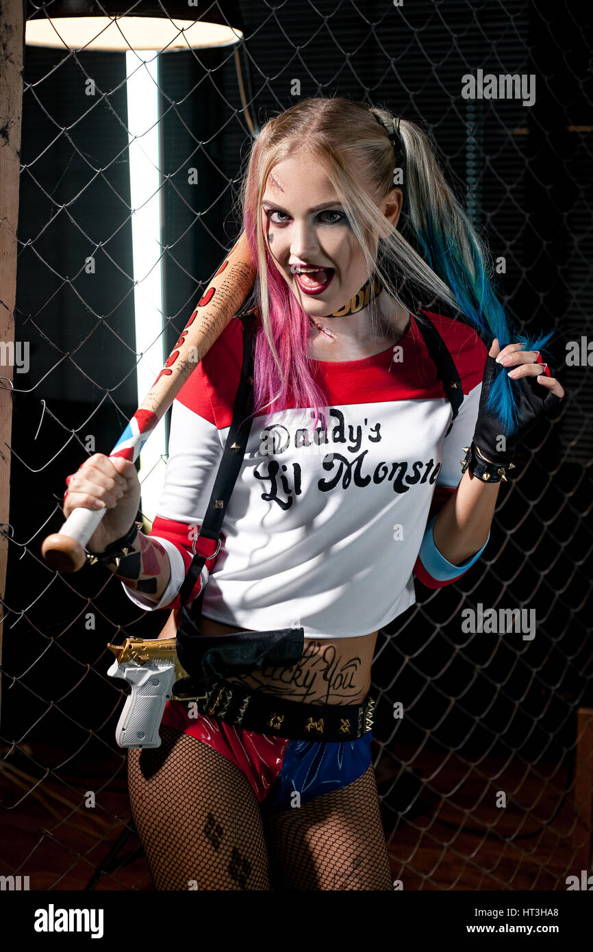 Girl in costume Harley Quinn. She stands with bat and gun. Close up. Cosplay. Stock Photo