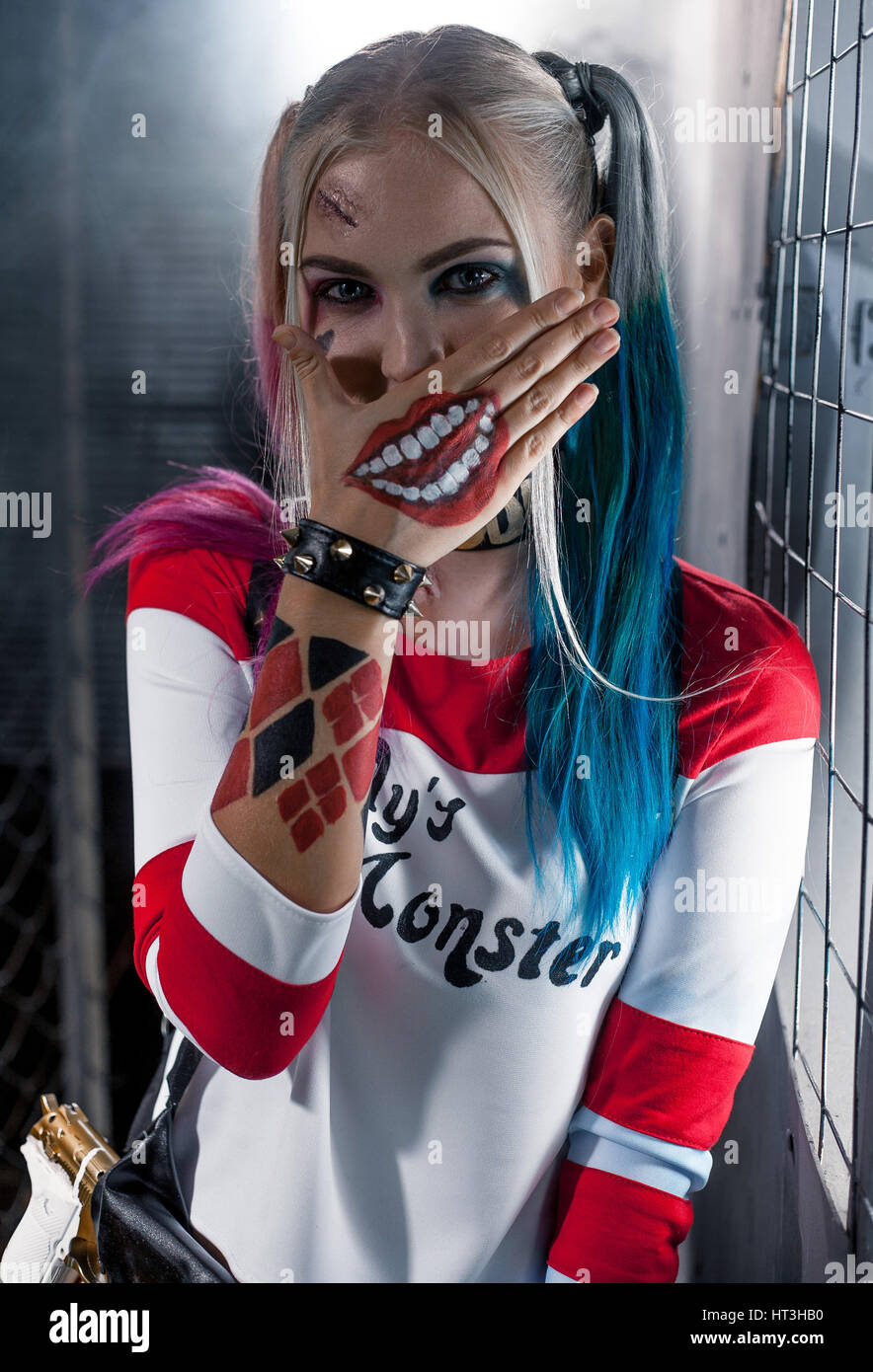 Portrait of smiling girl in costume Harley Quinn. She is near grid ...
