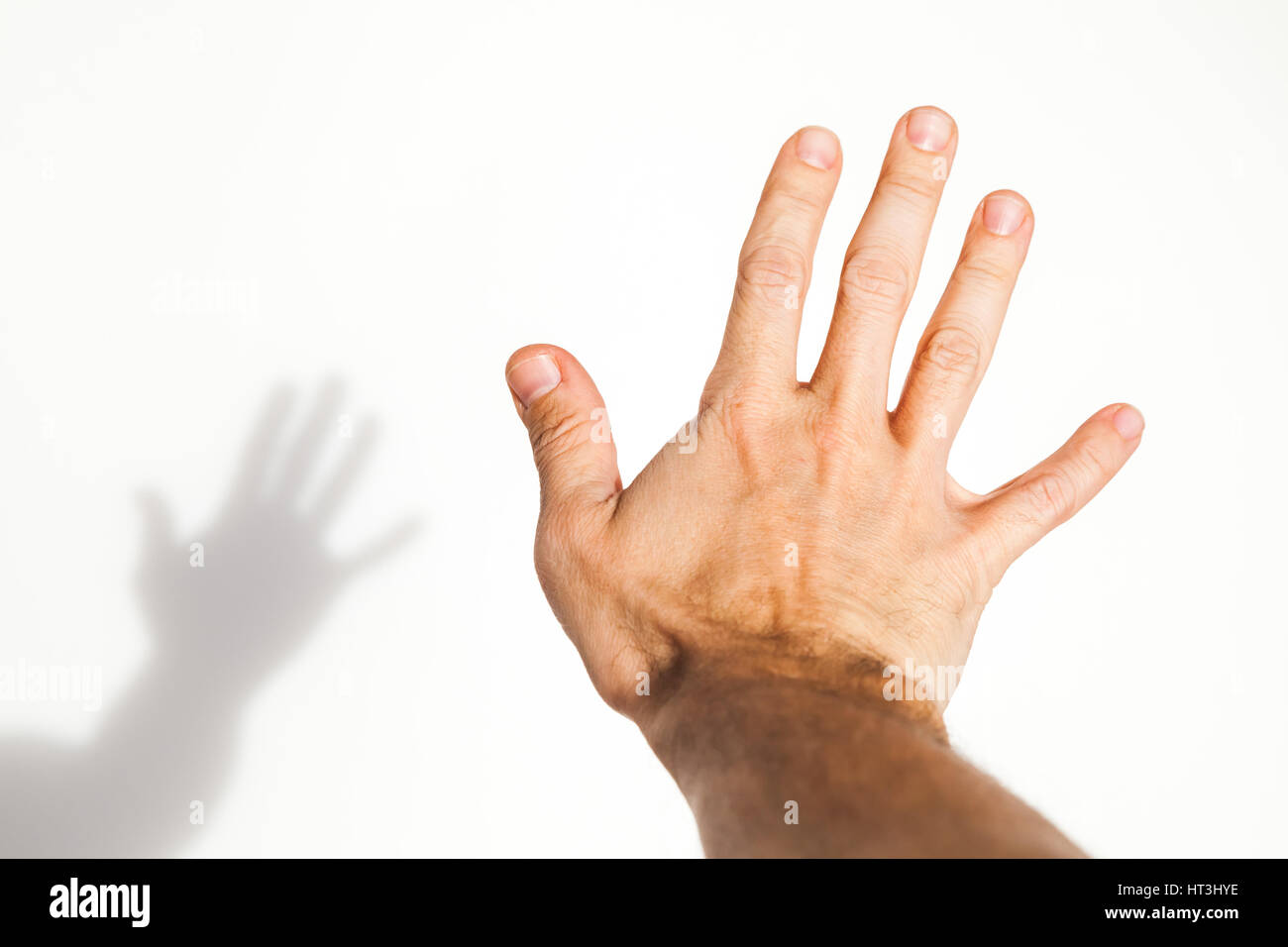 Male hand over white wall background with soft shadow, close up photo with selective focus Stock Photo