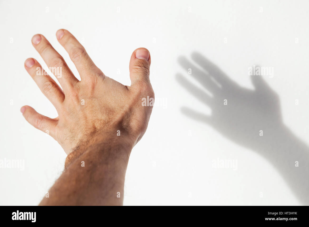 Male hand over white wall background with soft shadow, closeup photo with selective focus Stock Photo