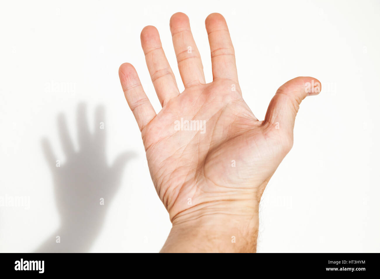 Open male hand over white wall background with soft shadow, closeup photo with selective focus Stock Photo