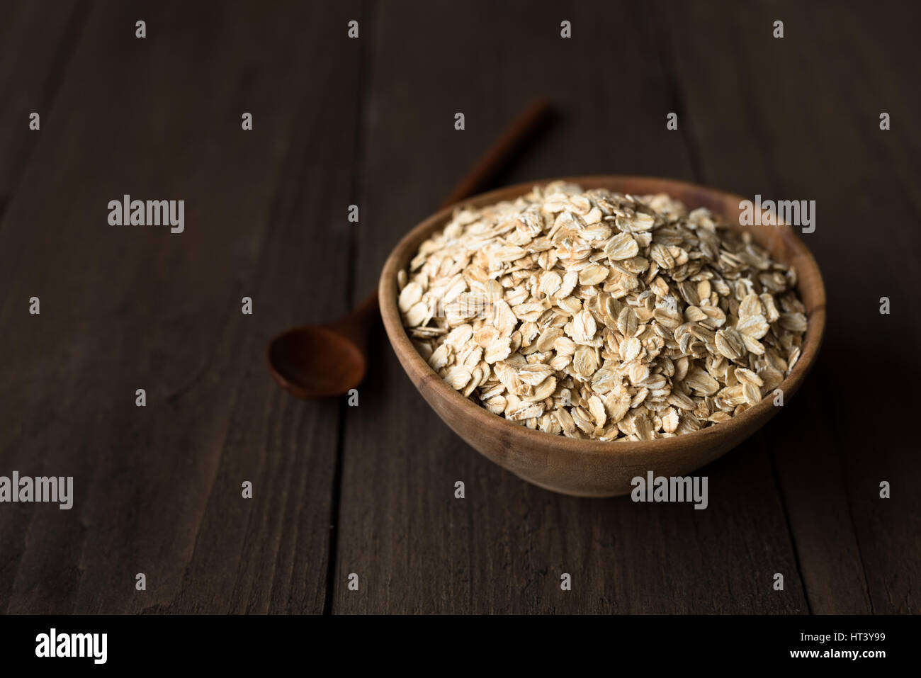 Oat flakes in old wooden bowl with wooden spoon Stock Photo