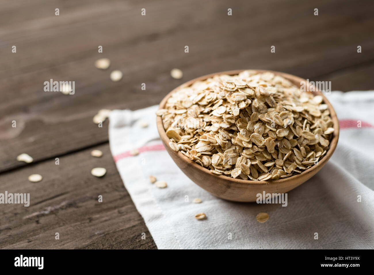 Oat flakes in old wooden bowl with white towel Stock Photo