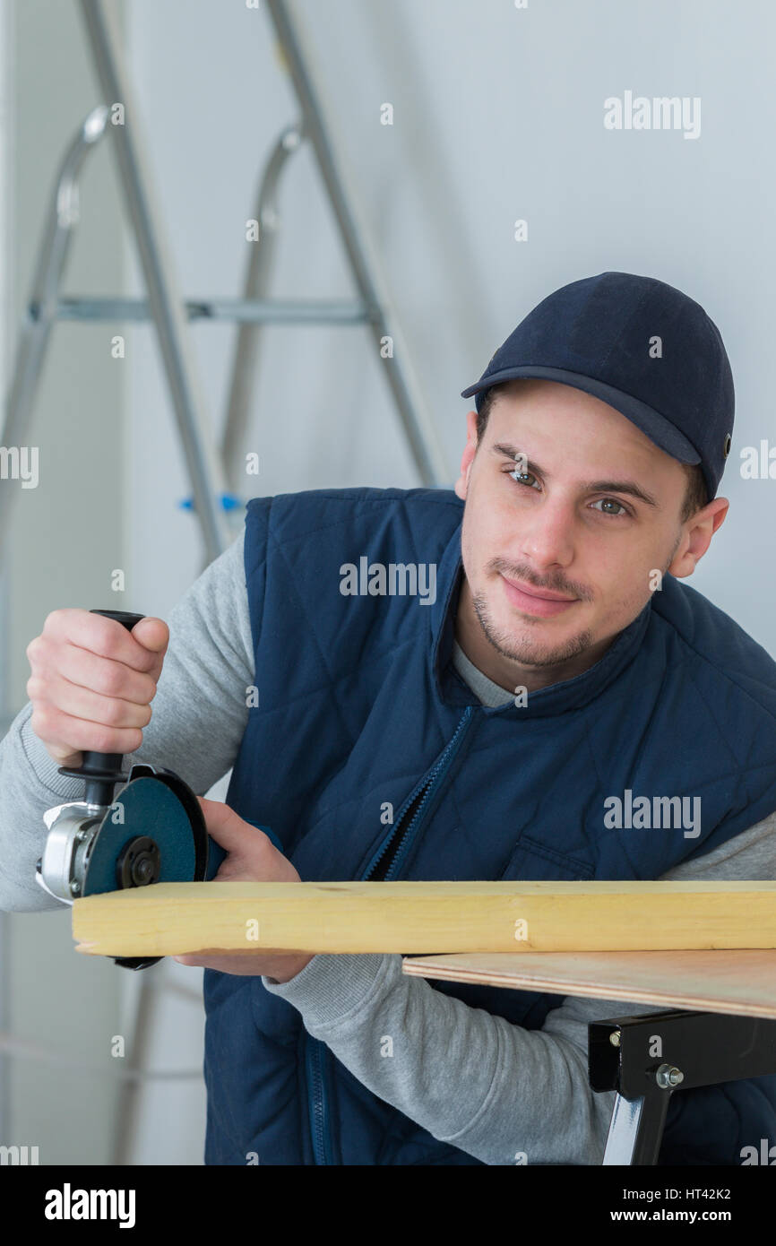 handsome carpenter using grinder on plank Stock Photo Alamy