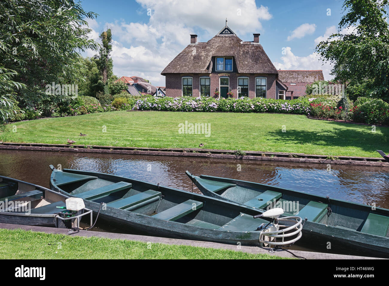 Giethoorn, Netherlands – June 29, 2016: Moored boats on the canal in the background house with a garden. Stock Photo