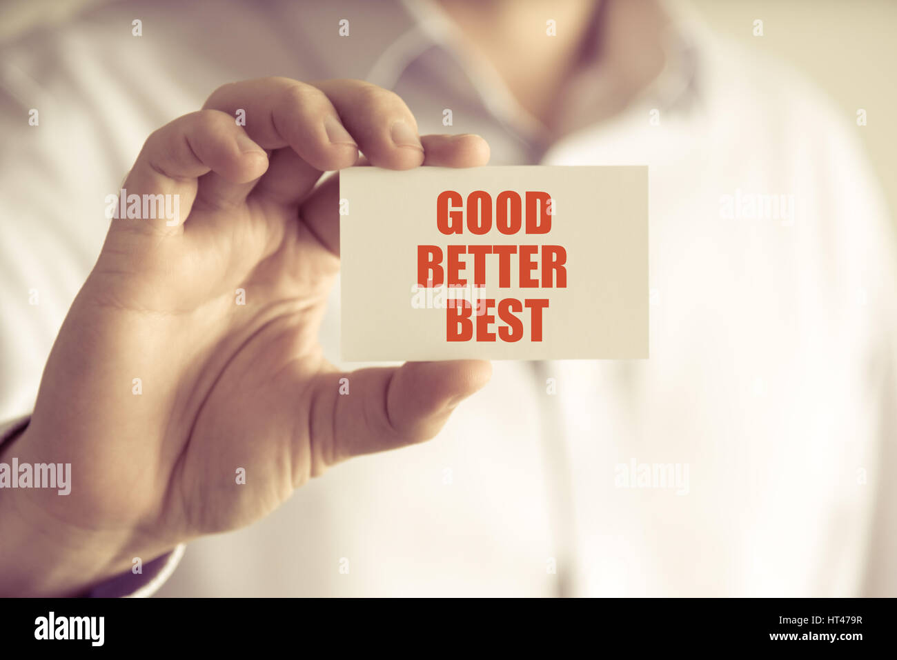 Closeup on businessman holding a card with text GOOD BETTER BEST, business concept image with soft focus background and vintage tone Stock Photo