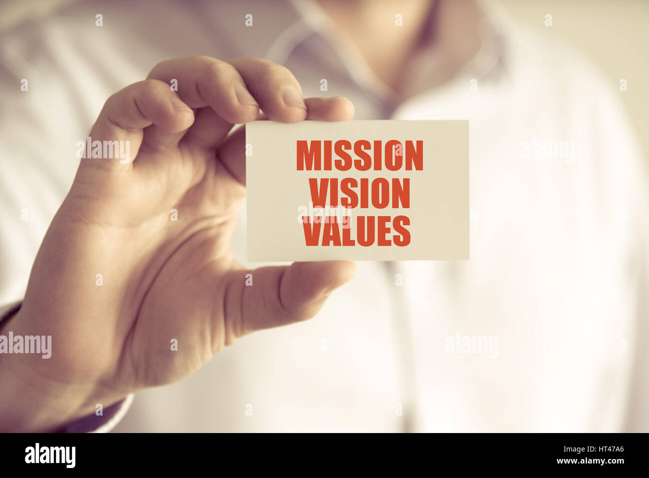Closeup on businessman holding a card with text MISSION, VISION, VALUES ...