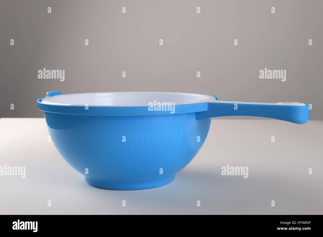 White plastic colander in red bowl isolated on white background Stock