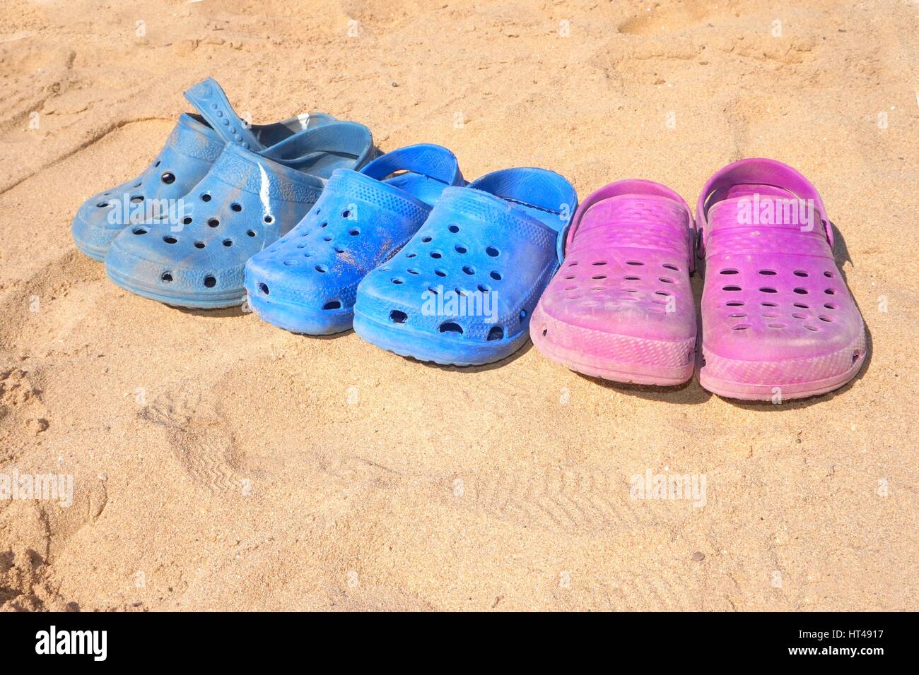 Row of kids plastic clogs on sunny beach Stock Photo - Alamy