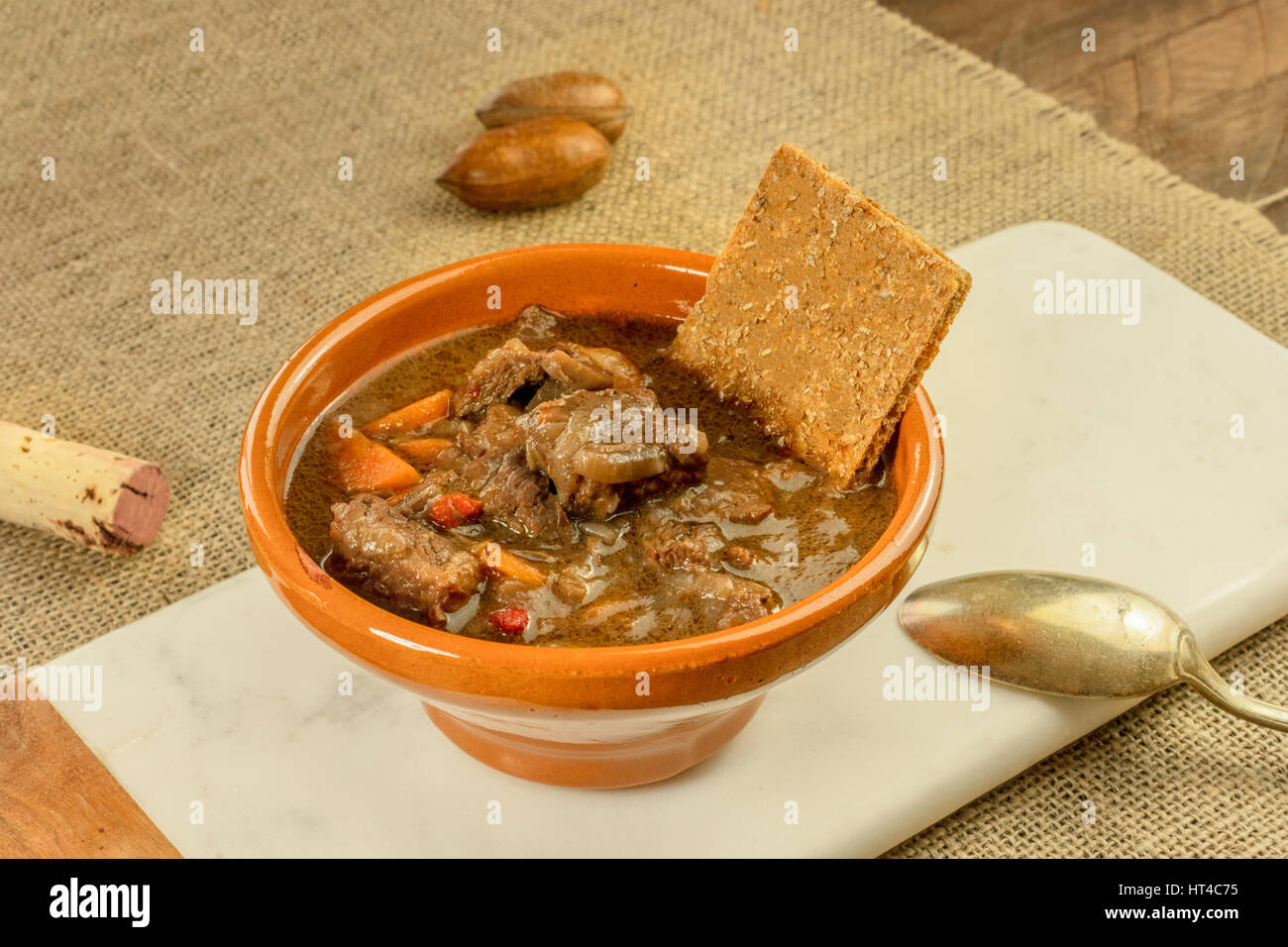 Meat and vegetable stew in an earthenware bowl, with a flatbread and a