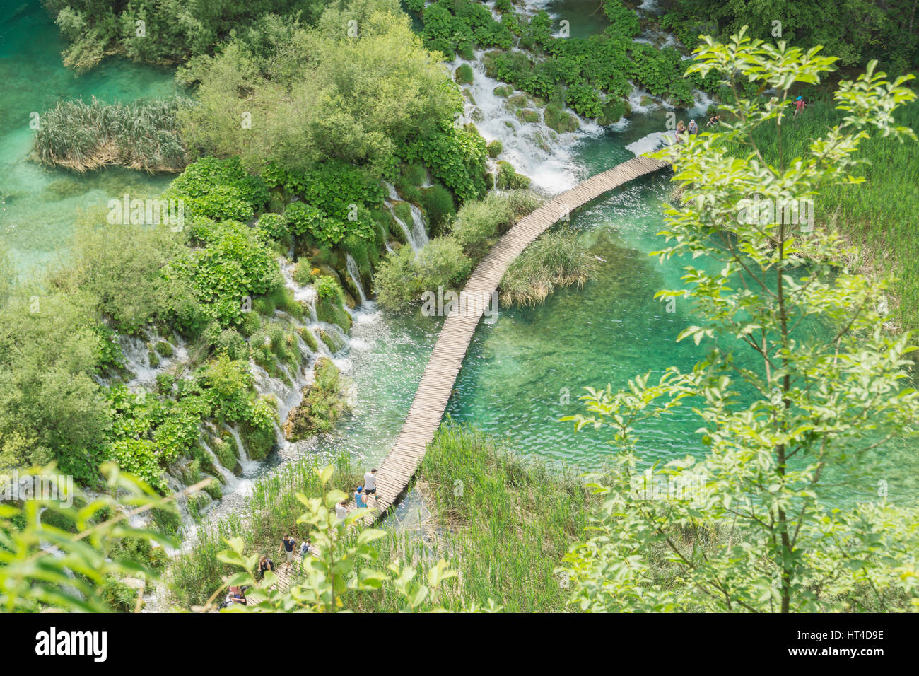 An aerial view of tourists entering a timber walkway across lakes and waterfalls at Plitvice National Park in Croatia. Stock Photo