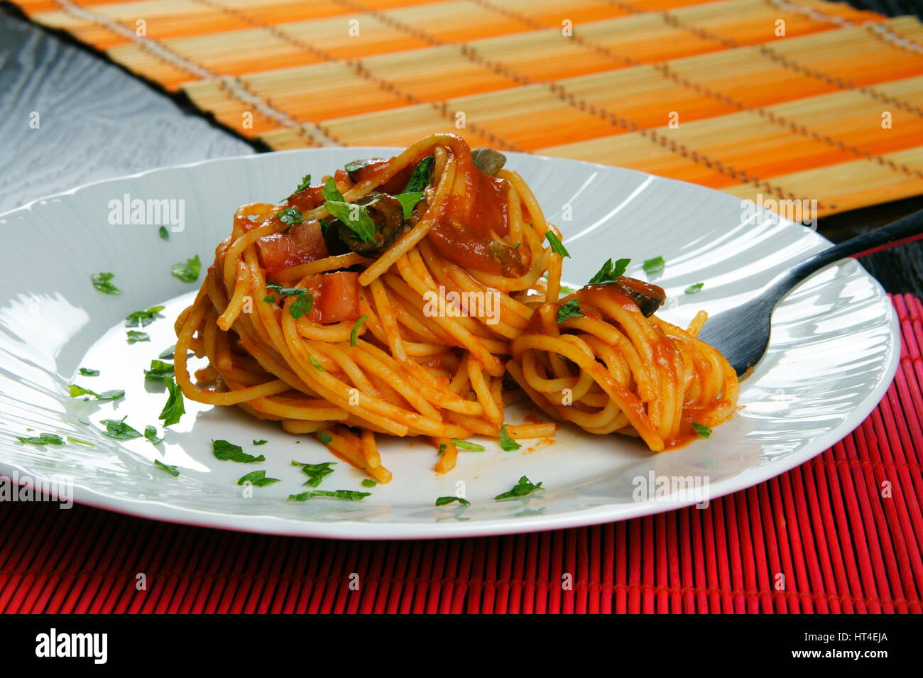 Spaghetti puttanesca with fork served in a white dish Italian recipe