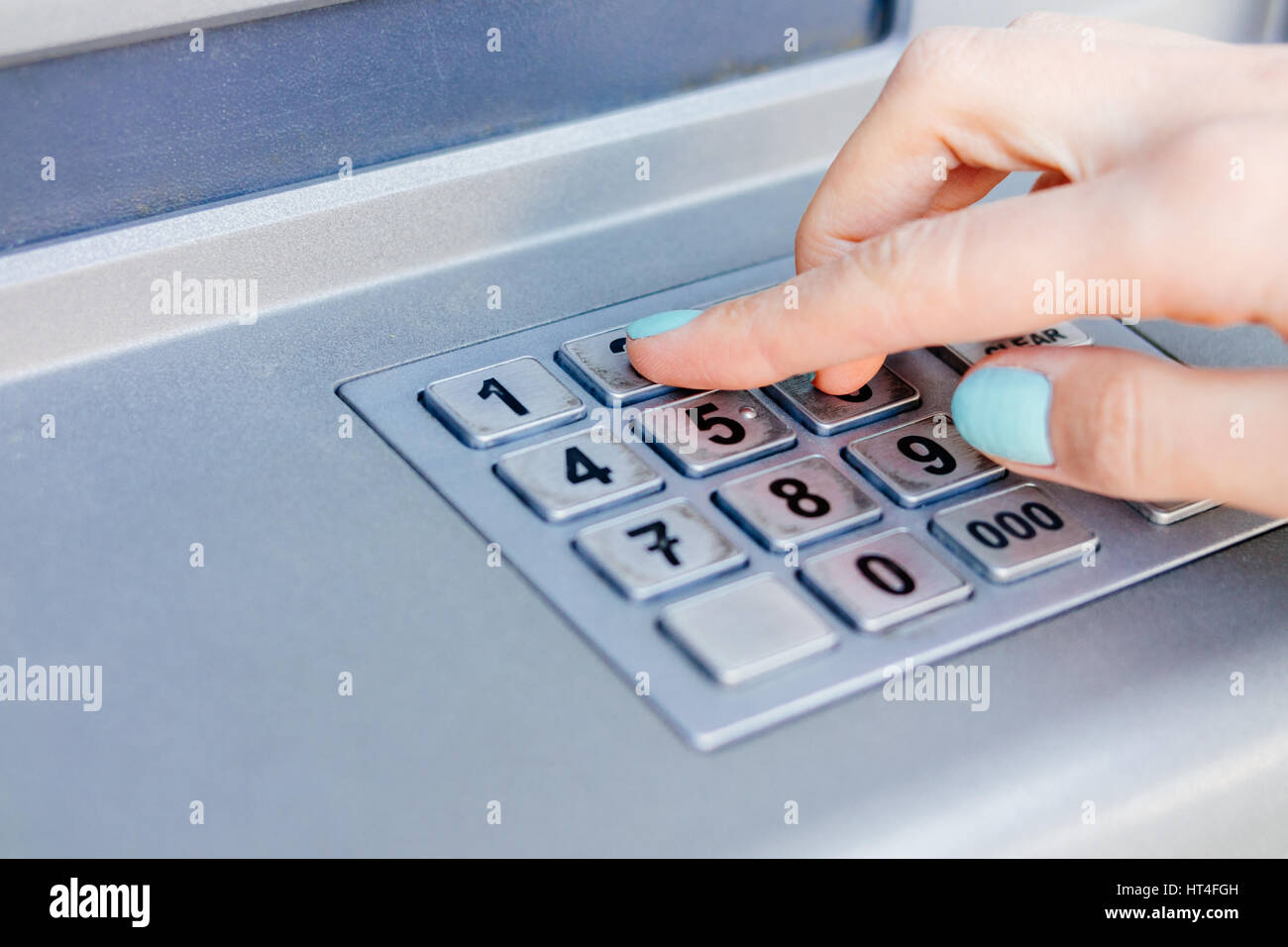Ladies hand dials the PIN code at an ATM close-up Stock Photo