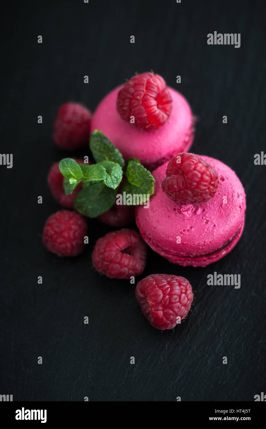 pink macaroons with raspberries on black background Stock Photo - Alamy