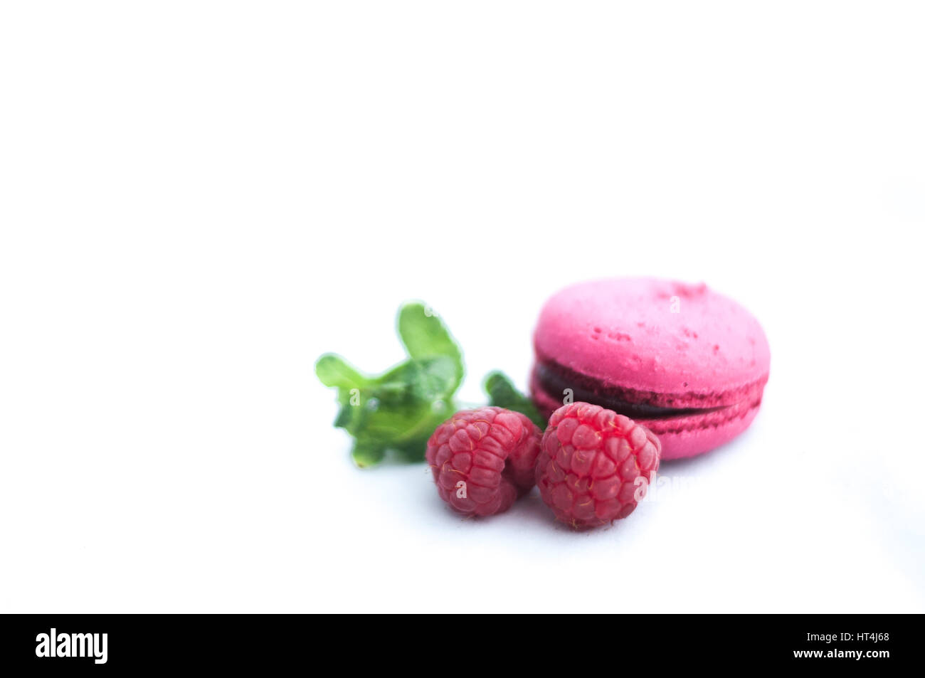 pink macaroons with raspberries on white background Stock Photo - Alamy
