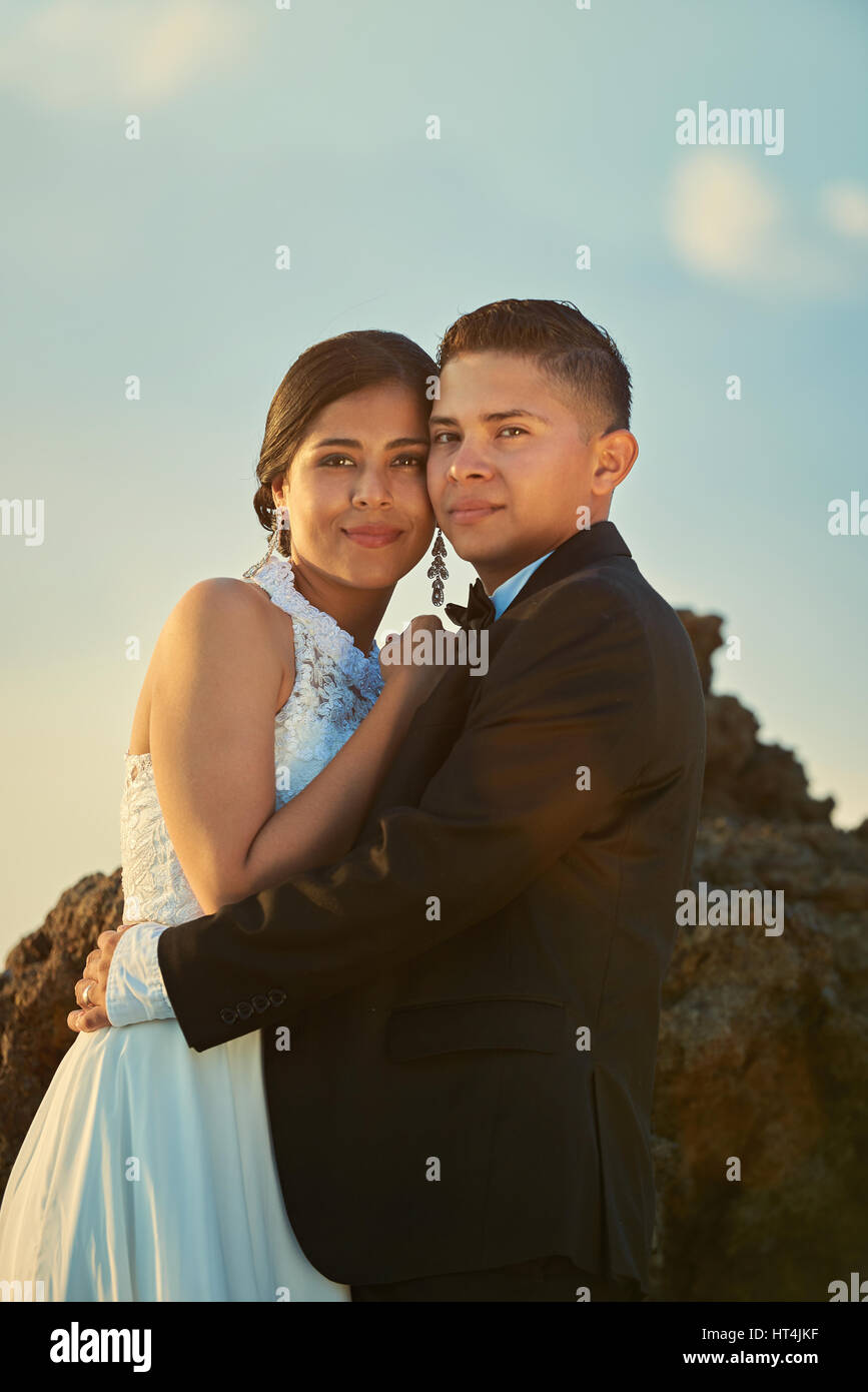 Portrait of happy young wedding couple on blue sunset sky background ...