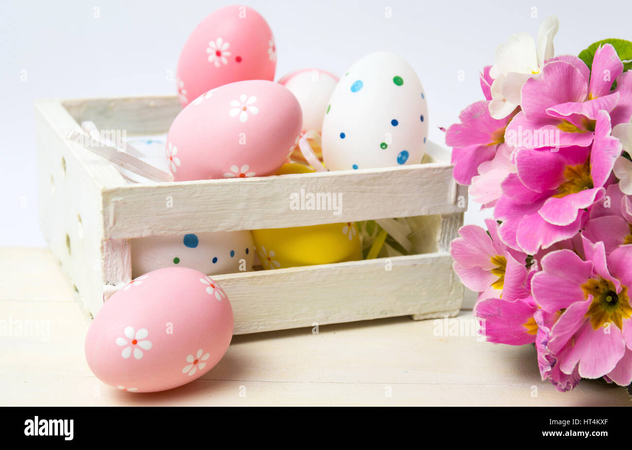 Painted Easter eggs in a wooden box and spring flowers Stock Photo
