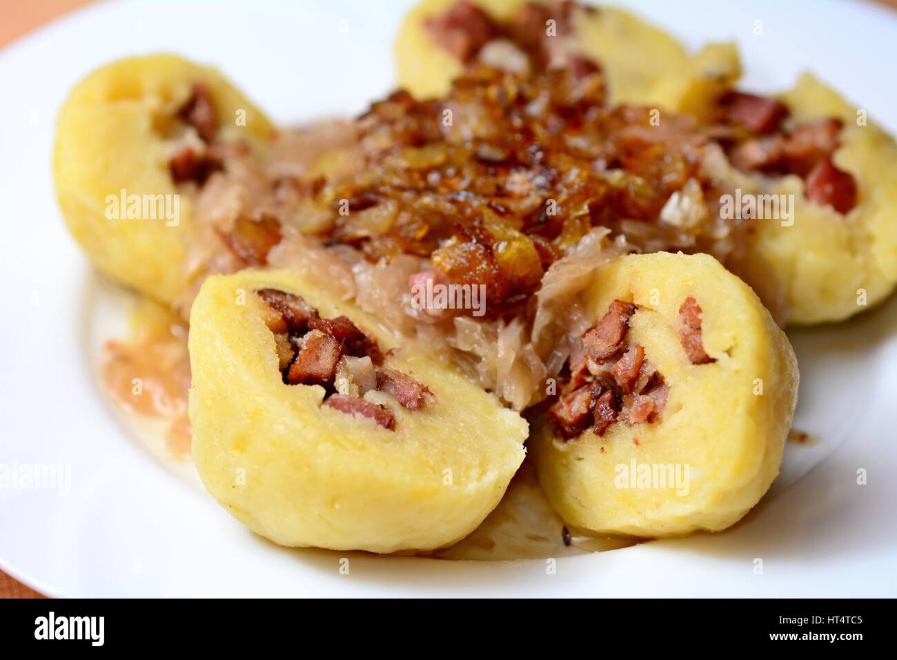 Portion of the sliced traditional czech potato dumplings stuffed with smoked meat, braised cabbage and fried onion. Stock Photo