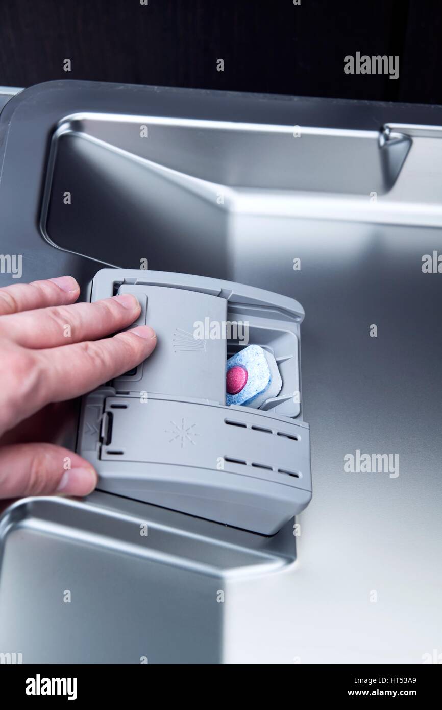 hand loads a dishwashing tablet into a dishwasher Stock Photo Alamy