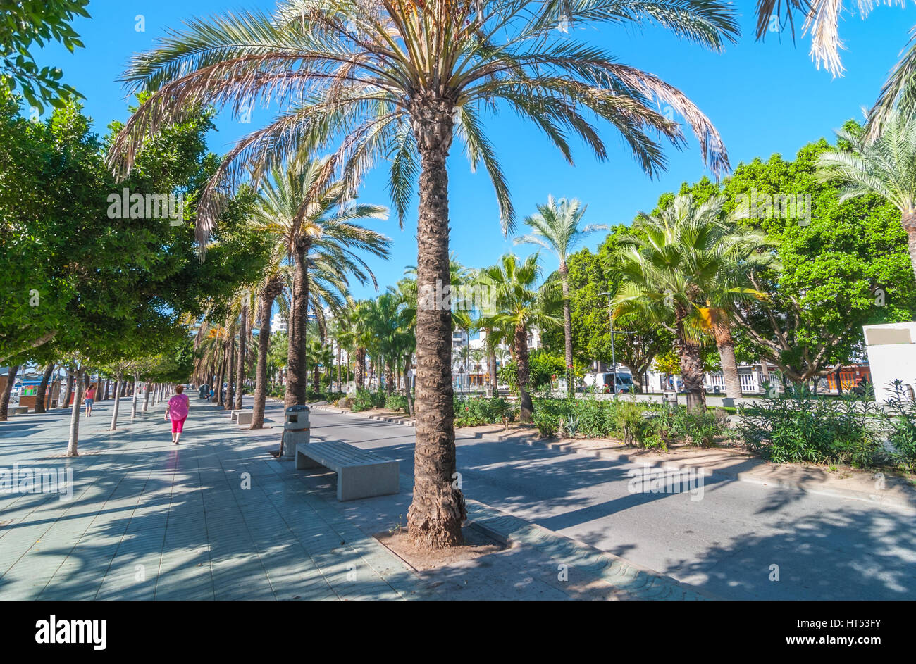 Two women walk along main boardwalk, now a stone concourse, beside the beach in street of Sant Antoni de Portmany, Ibiza, Spain. Stock Photo